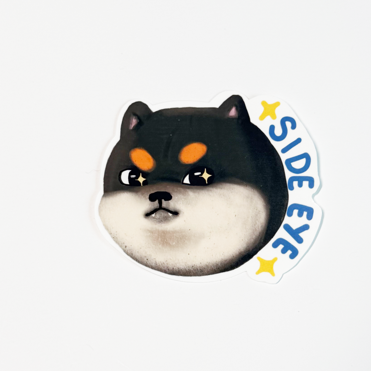 A die-cut sticker featuring a cartoon Shiba Inu dog face with orange eyes and the text 'SIDE EYE' in blue with yellow stars, shown on a plain white background.