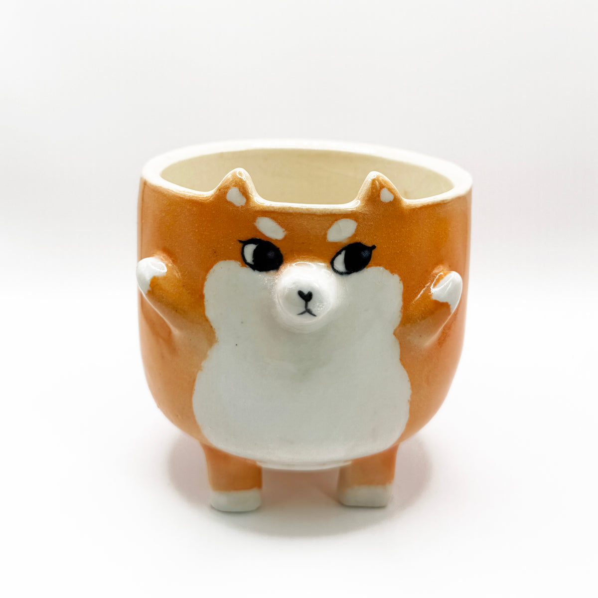 Orange colored shiba inu mug with side eyes. The shiba's two hands are up and it has a tail on the bottom of the mug